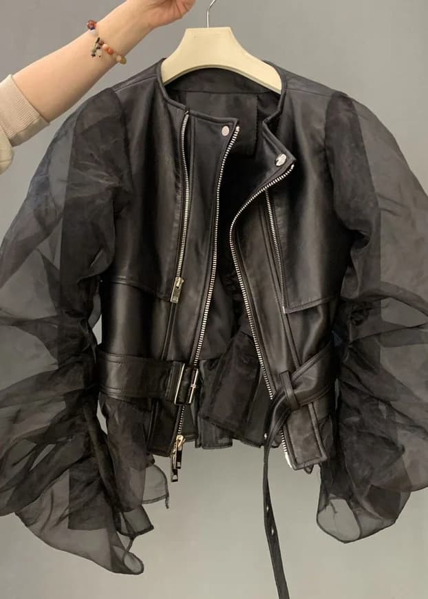 A black leather jacket with sheer organza sleeves, held up on a hanger