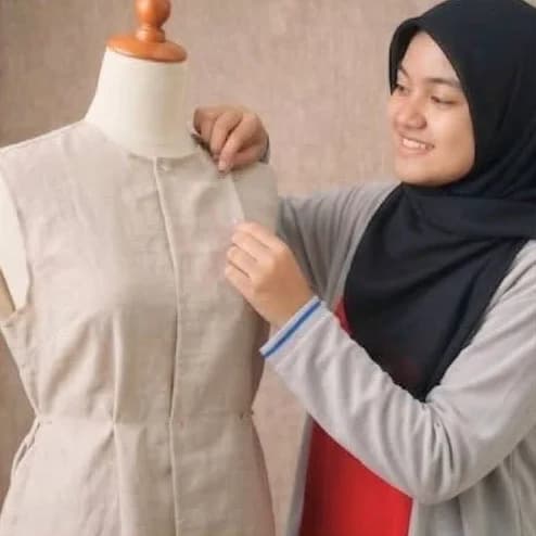 Nur Aina Natashah adjusting a linen dress on a dress form