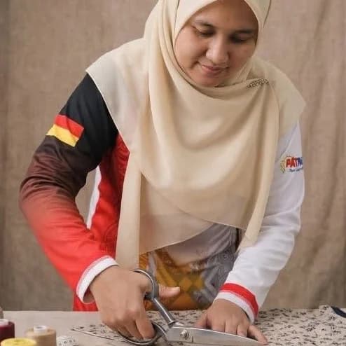Siti Humairah bt Mohd Yasin cutting fabric at the work table